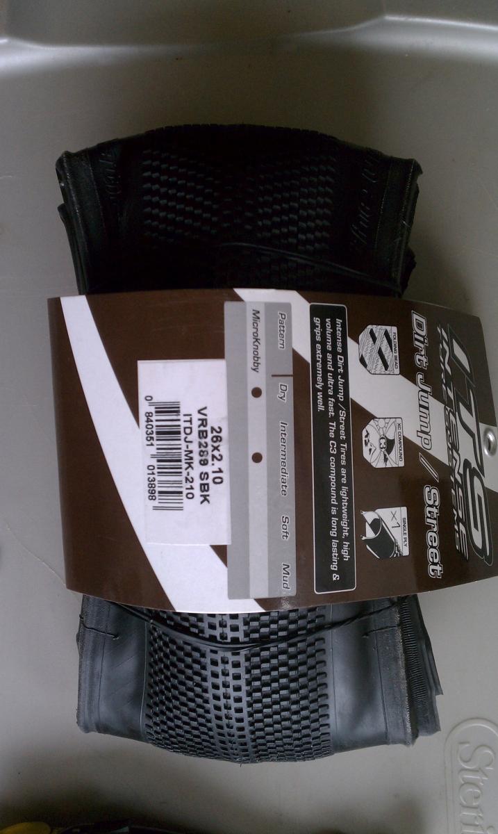 ITS Micro Knobby: Image of a dirt jump/street tire displayed on a neutral background. The tire has a MicroKnobby pattern designed for various terrains, with visible branding and specifications on the attached label. The label includes details such as size (26x2.10), model number (VRB26SBK), and notes about tire performance in dry, intermediate, and muddy conditions.