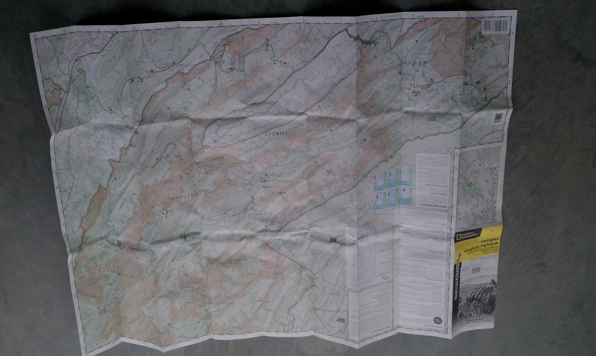 National Geographic Trails Illustrated #788 Covington Aleghany Highlands: A detailed topographic map laid out on a flat surface, displaying various terrain features, elevation contours, and location markers. The map includes information about recreational areas and highlights notable landmarks, with a yellow section labeled "Covington/Allegheny Highlands" on the bottom right.