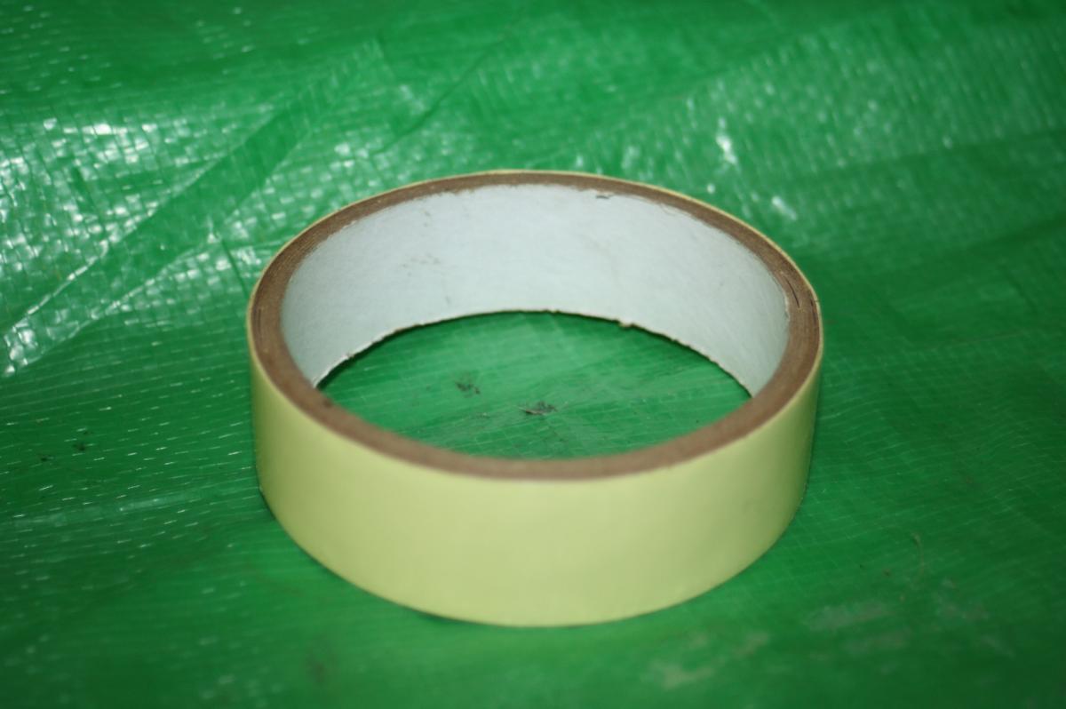 Stans Standard Kit: A roll of yellow masking tape resting on a green textured surface.