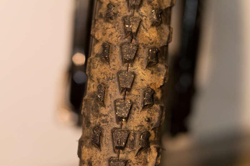 Specialized Resolution Sport: Close-up of a muddy mountain bike tire showcasing its rugged tread pattern and clay-like dirt accumulation.