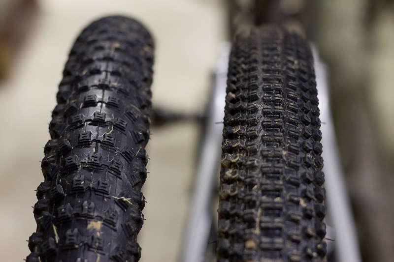 Kenda Small Block Eight: Close-up view of two mountain bike tires side by side, illustrating their tread patterns. The left tire has a rough, heavily worn surface, while the right tire appears cleaner and less used. The background is softly blurred, focusing on the details of the tires.