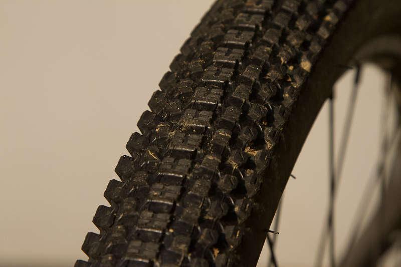 Kenda Small Block Eight: Close-up of a mountain bike tire showing detailed tread pattern and some dirt, set against a neutral background.