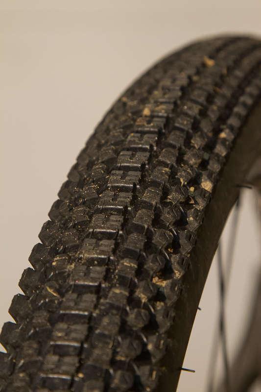 Kenda Small Block Eight: Close-up of a bicycle tire showcasing its textured tread pattern, with hints of dirt and debris visible.
