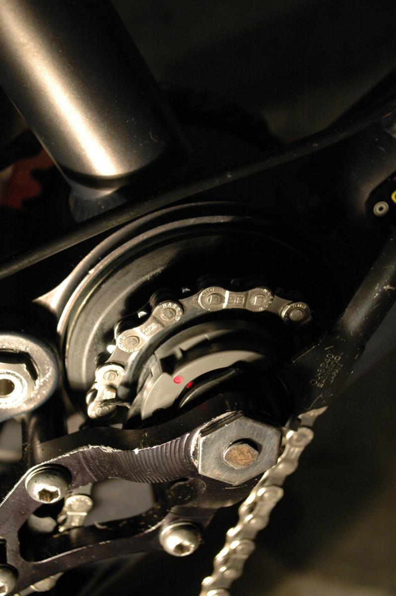Shimano Nexus Hub: Close-up image of a bicycle's drivetrain, showing the gear mechanism, chain, and cog. The photo highlights metal components with detailed textures and a shadowy background, emphasizing the mechanical aspects of the bike.