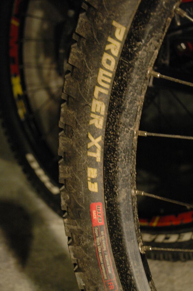 WTB Prowler MX: Close-up image of a mountain bike tire labeled "PROWLER XT 2.3," showing dirt and tread patterns, with a partially visible rim and spokes in the background.