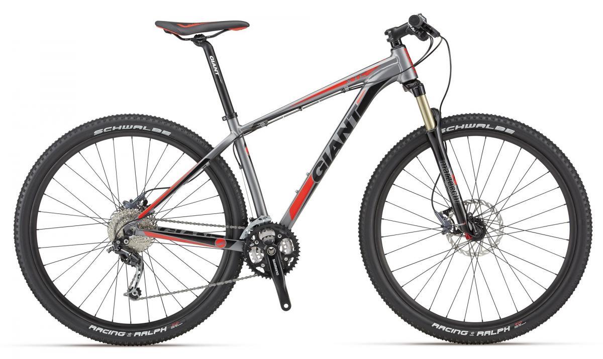 Giant XTC 29er 2: Mountain bike with a gray and red frame, featuring 29-inch wheels with Schwalbe Racing Ralph tires, a Shimano drivetrain, and front suspension. The bike has a sleek design, suitable for off-road adventures.