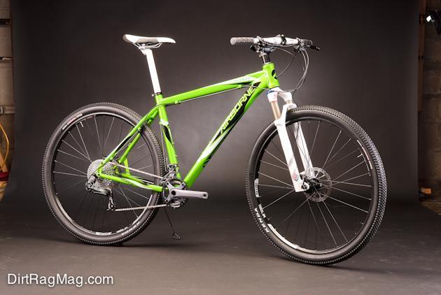 Airborne Goblin: A vibrant green mountain bike with a sleek design, featuring front suspension and large wheels, displayed against a dark background. The bike has disc brakes and a modern frame, showcasing its suitability for off-road cycling.