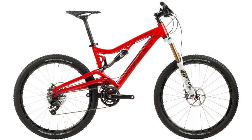Santa Cruz Nickel: A bright red mountain bike featuring a lightweight frame, wide tires, and a suspension system. The bike is displayed from the side, showcasing its design, including a front fork with a white finish and a modern gearing system.