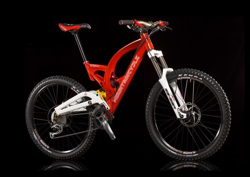 Mountain Cycle San Andreas: A bright red mountain bike with a sleek design, featuring a white frame section and equipped with thick tires suitable for rugged terrain. The bike is positioned against a black background, highlighting its features such as the front suspension and disc brakes.