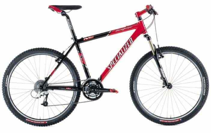 Specialized Stumpjumper: A black and red mountain bike with a lightweight frame, featuring thick tires and a gear shifter. The bike is designed for off-road terrain, showcasing a sturdy front suspension and dual brakes. The brand name "Specialized" is prominently displayed on the frame.