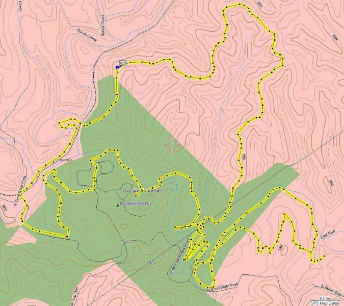 Map showing hiking trails and topographic features, with yellow dashed lines indicating paths, green shaded areas representing park land, and contour lines in pink. Key landmarks and roadways are labeled, providing routes for outdoor activities. North Bend State Park mountain bike trail.