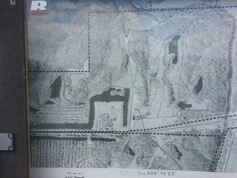 A detailed map displaying various terrain features, bodies of water, and pathways. The map is partially shaded, showing contours and outlines. A labeled point indicates "You Are Here," providing a reference for navigation. The overall layout includes dotted and dashed lines marking different areas, likely for hiking or recreational purposes. Wildlife Prairie Park mountain bike trail.