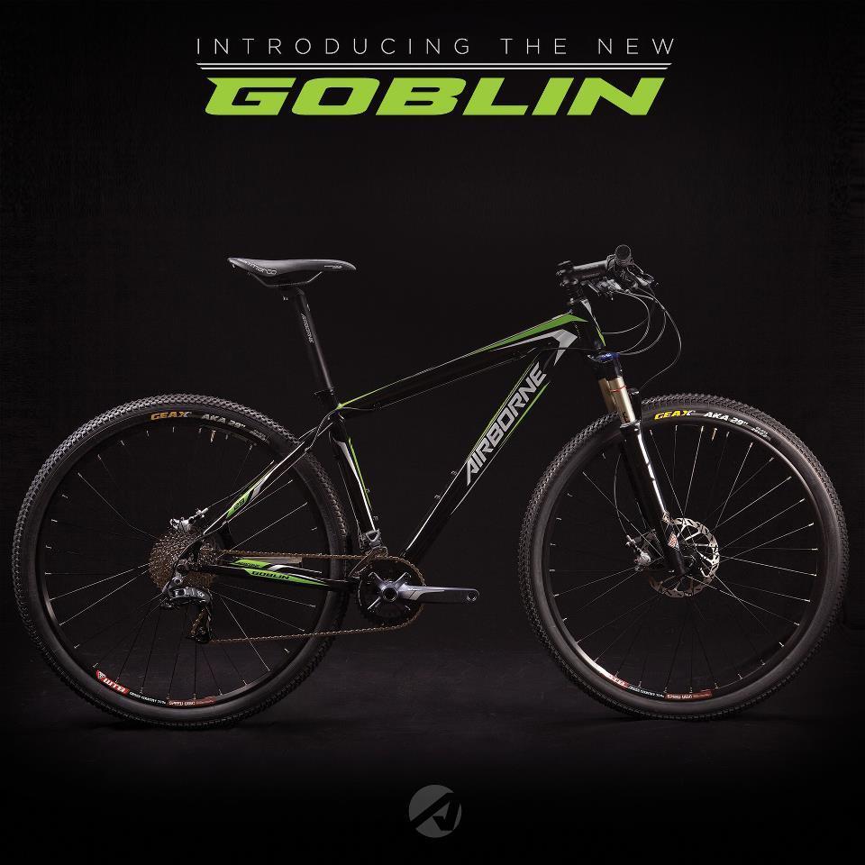 Airborne Goblin: A modern mountain bike displayed against a dark background, featuring a sleek black frame with green accents. The bike is equipped with thick tires, front suspension, and a gear system, prominently showcasing the brand name "Airborne" on the frame. Text at the top announces its name as "Introducing the New Goblin."
