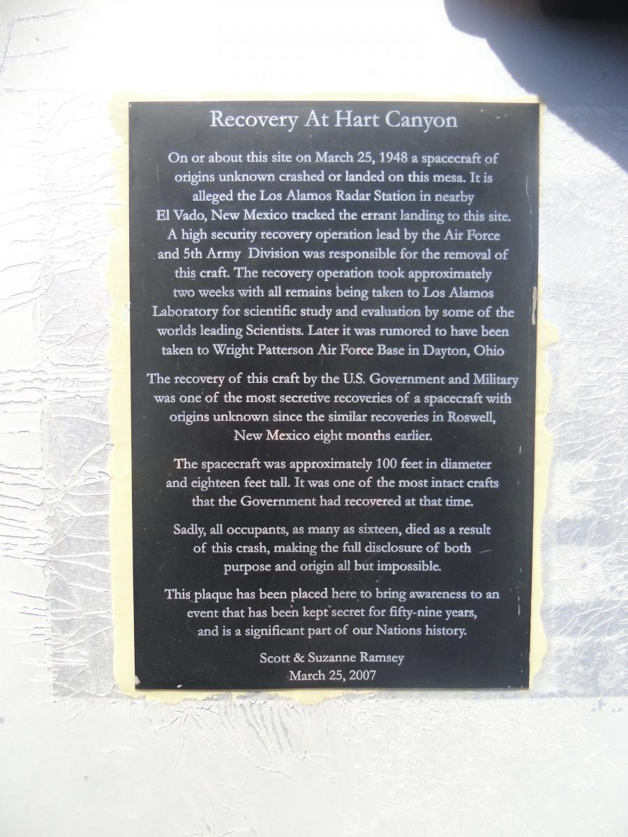 Plaque titled "Recovery At Hart Canyon" detailing the crash of an unidentified spacecraft on March 25, 1948. The text discusses the high-security recovery operation led by the U.S. Air Force and the 5th Army Division, noting the transfer of remains to Los Alamos Laboratory and suggesting a connection to UFO events. It mentions the size of the spacecraft and the fatalities involved, emphasizing the secrecy surrounding the incident and its significance in U.S. history. The plaque is attributed to Scott and Suzanne Ramsey, dated March 25, 2007. Alien Run Trail mountain bike trail.