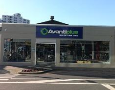 Image of an Avantiplus bike shop, showcasing a modern storefront with large glass windows displaying bicycles and cycling accessories. The shop