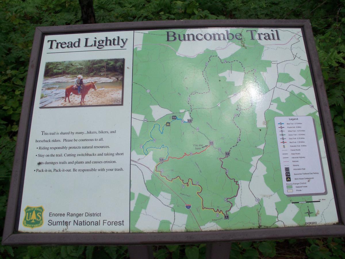 Sign for the Buncombe Trail in Sumter National Forest. The sign includes a map of the trail and surrounding area, along with guidelines for using the trail responsibly, such as being courteous to hikers, bikers, and horseback riders and cleaning up trash. A small photo of a person riding a horse is included. Buncombe - Brickhouse Recreation Area mountain bike trail.
