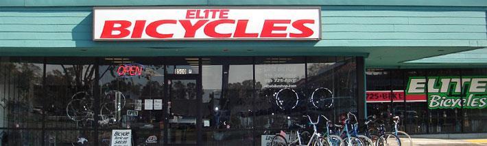 A storefront of a bicycle shop named "Elite Bicycles," featuring a large sign with the shop