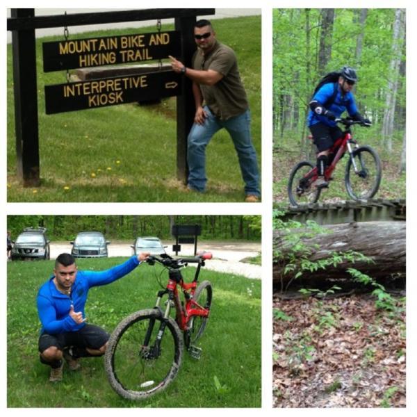 A collage of four images related to mountain biking and hiking. The top left image shows a person pointing at a sign for a "Mountain Bike and Hiking Trail" near an interpretive kiosk. The top right image features a mountain biker on a trail, navigating over a log. The bottom left image shows another person kneeling next to a red mountain bike. The bottom right image displays a close-up of the forest floor with greenery and fallen leaves. Brown County Park mountain bike trail.