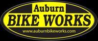 Logo for Auburn Bike Works featuring an oval shape with a yellow background and black text. The text reads "Auburn" at the top, "BIKE WORKS" in larger font at the center, and includes the website address "www.auburnbikeworks.com" at the bottom.