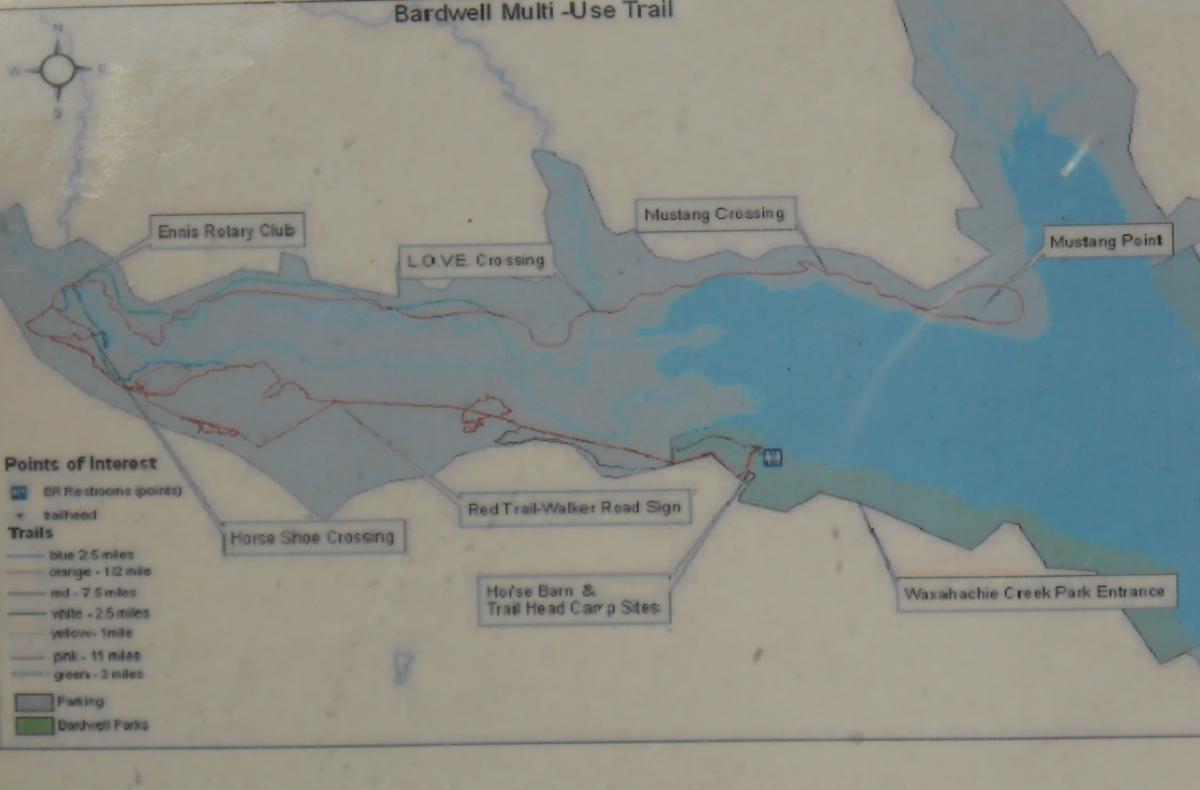 Map of the Bardwell Multi-Use Trail, showing various trails and points of interest including Ennis Rotary Club, LOVE Crossing, Mustang Crossing, and parking areas. The map includes different trail lengths indicated by color codes, with blue, red, orange, white, yellow, pink, and green trails noted.  Bardwell Lake mountain bike trail.