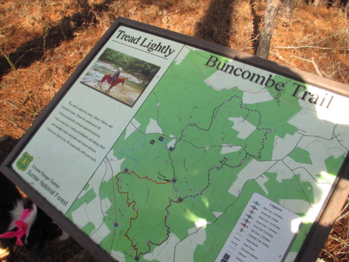 Information sign for Buncombe Trail in the Sumter National Forest, featuring a map of the area and guidelines for responsible hiking and horseback riding. The sign includes text about trail use and conservation, alongside a small photo of a person on horseback. Buncombe - Brickhouse Recreation Area mountain bike trail.