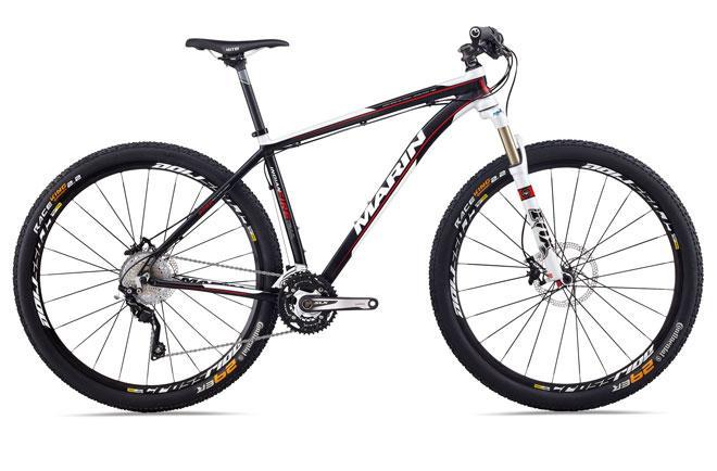 Marin Indian Fire Trail 29er: A black and red Marin mountain bike with a lightweight aluminum frame, front suspension fork, and wide tires. The bike features disc brakes, a chainring, and a gear shifter on the handlebars, showcasing a sleek design suitable for off-road cycling.