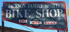 A sign for Jackson Family Sports Bike Shop, featuring the words "Bike Shop" prominently in large letters, and icons representing BMX, MTB, and road biking.