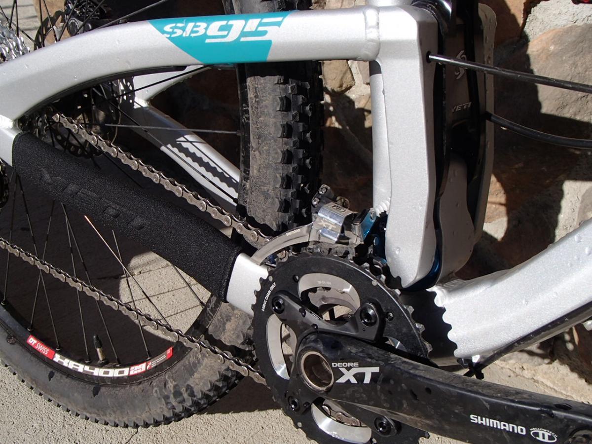 Yeti SB95: Alt text: Close-up of the drivetrain on a mountain bike, showcasing the Shimano Deore XT crankset, chain, and a part of the bike frame with visible branding and details.