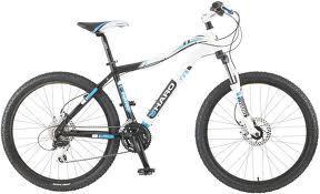 Haro Flightline Sport: A black and white mountain bike with blue accents, featuring thick tires, a sturdy frame, and a front suspension system. The handlebars are equipped with grips, and the bike has a gear shifter near the pedals.