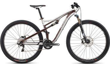 Specialized Camber 29: A brown and white mountain bike with thick tires, front suspension, and a variety of gears, displayed against a neutral background.