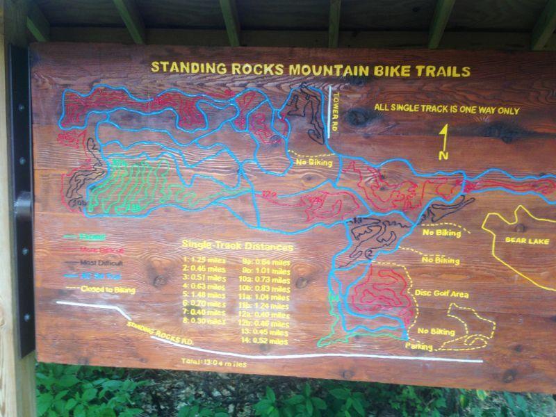 Map of the Standing Rocks Mountain Bike Trails, displaying various trail routes and distances. The map indicates different levels of difficulty with color codes: easy (green), moderate (blue), and most difficult (red). It also highlights areas where biking is prohibited, parking locations, and nearby features like Bear Lake and a disc golf area. Total trail length is noted as 13.04 miles. Standing Rocks mountain bike trail.