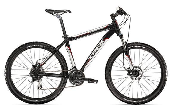 Black mountain bike with red accents, featuring front suspension, disc brakes, and Bontrager tires. The bike's frame is branded with the Trek logo.