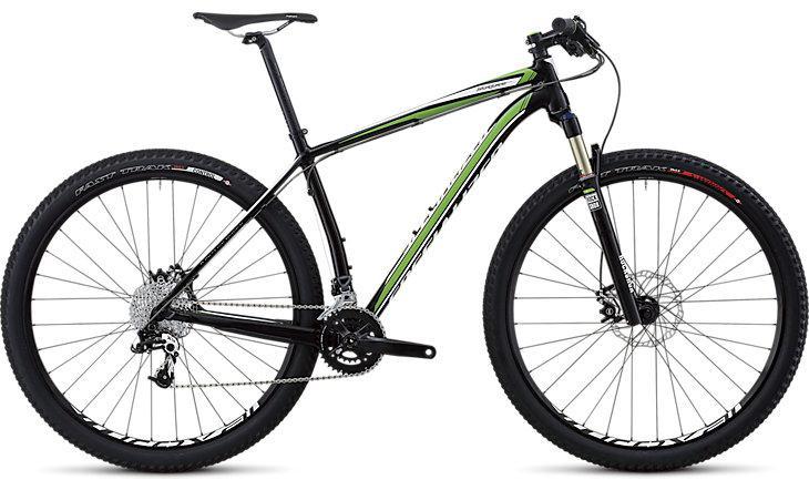 Specialized Stumpjumper Comp: A black and green mountain bike with a lightweight frame, featuring front suspension and wide tires designed for off-road terrain. The bike includes a gear system and disc brakes, showcasing a sleek and modern design.