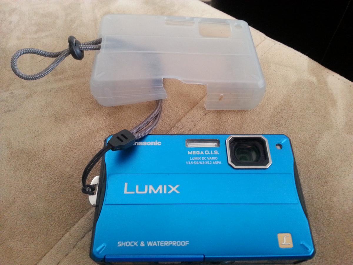 Panasonic Lumix DMC TS10: A blue Panasonic Lumix waterproof camera with a clear protective case, displayed on a soft, beige surface.
