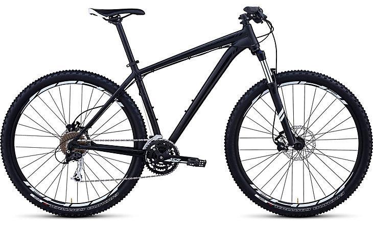 Specialized Rockhopper Comp 29: A black mountain bike featuring a lightweight frame, wide tires, and a gear system designed for off-road riding. The bike has disc brakes and is positioned on a white background.