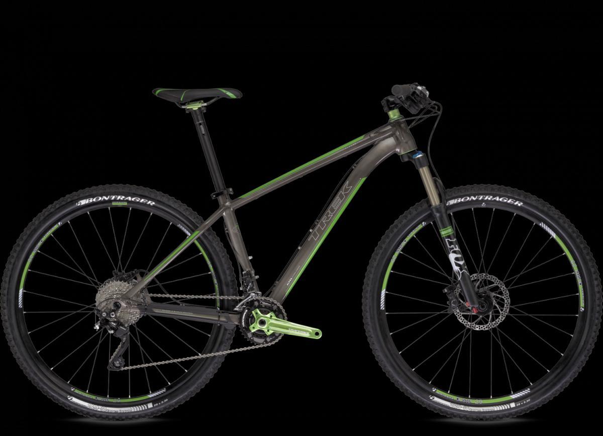 Trek Stache 8: Alt text: A side view of a Trek mountain bike featuring a gray frame with green accents, equipped with black tires and disc brakes. The bike has a sleek design suitable for off-road riding.