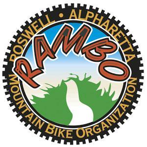 Logo of the RambO (Roswell Alpharetta Mountain Bike Organization) featuring the word "RAMBO" in bold, stylized letters, surrounded by a circular design that includes a tree and a winding path against a blue sky background. The text also indicates the organization's focus on mountain biking.