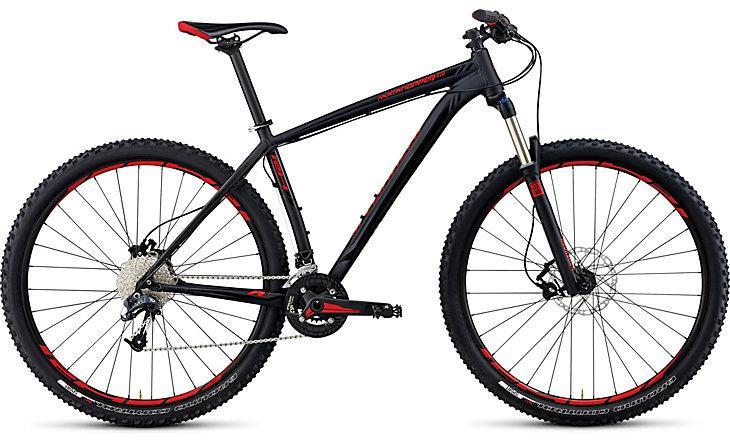 Specialized Rockhopper Pro EVO 29: A sleek black mountain bike with red accents, featuring wide tires, a front suspension fork, and a Shimano gear system, positioned against a plain background.