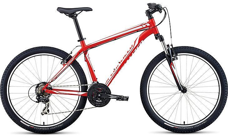 Specialized Hardrock 26: A red mountain bike with a lightweight frame, front suspension, and knobby tires designed for off-road riding. The bike features a black seat and handlebars, and it's positioned against a plain background.