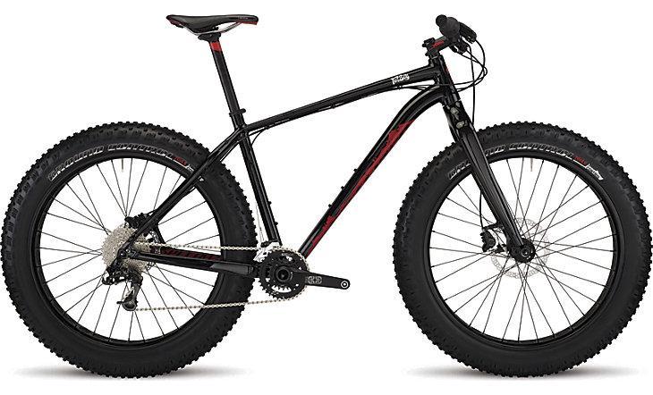 Specialized Fatboy Expert: A black and red fat bike with wide tires, featuring a modern frame design, disc brakes, and a single chainring drivetrain. The bike is designed for off-road terrain, highlighting its robust construction suitable for various riding conditions.