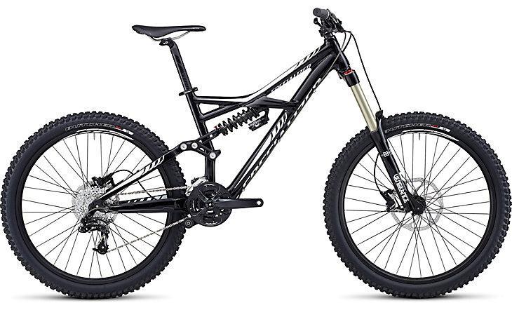 Specialized Enduro: A black mountain bike with a dual suspension frame, featuring wide tires and disc brakes, positioned on a white background. The bike has a prominent front fork and a gear system, designed for rugged terrain.