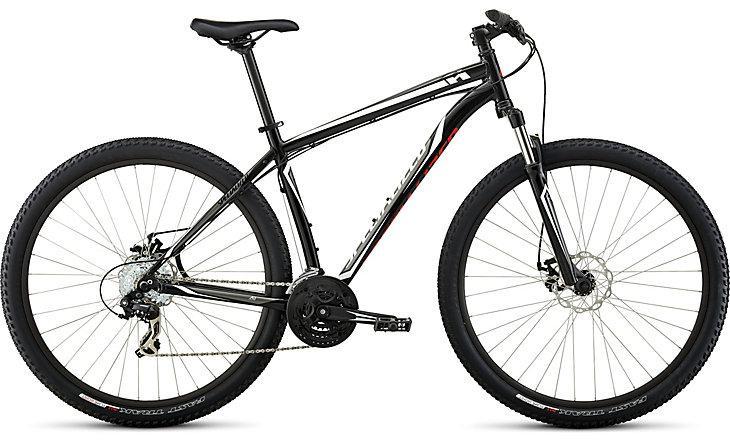 Specialized Hardrock Disc SE 29: A black mountain bike with red accents, featuring wide tires, disc brakes, and a front suspension fork, positioned against a neutral background.