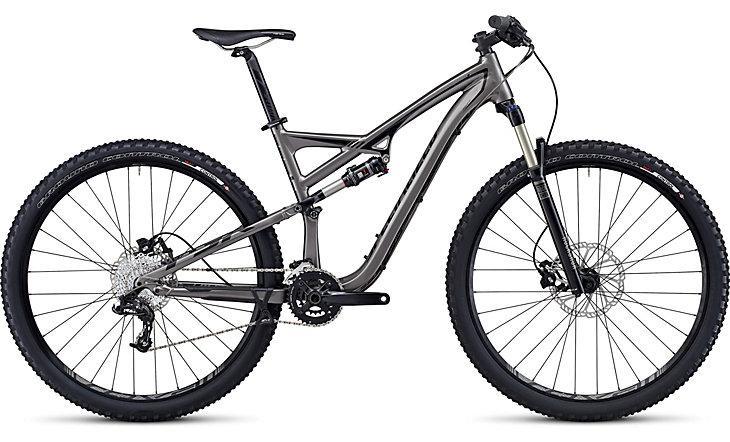 Specialized Camber Comp 29: A modern mountain bike with a sleek gray frame, wide tires, and front suspension. The bike features disc brakes, a gear shifter, and a lightweight design, suitable for off-road trails and rugged terrain.