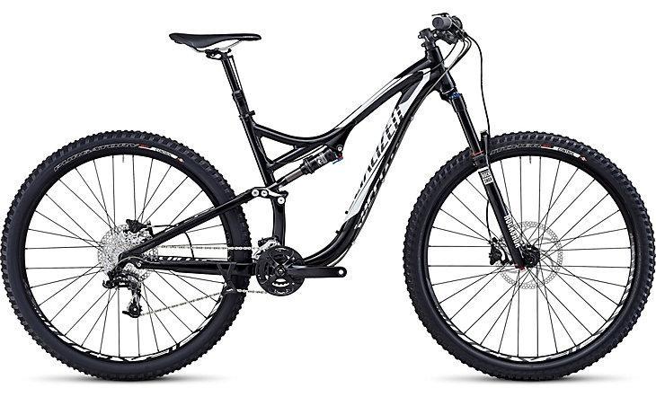 Specialized Stumpjumper FSR Comp EVO 29: A black and white mountain bike featuring a full suspension design, wide tires, and disc brakes, positioned against a neutral background. The bike has a sleek frame with a modern aesthetic, ideal for off-road cycling.