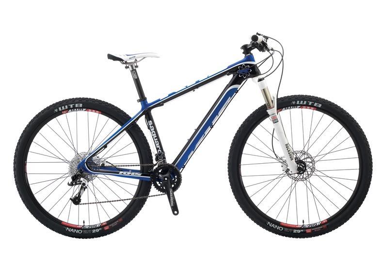 KHS Saguaro: A blue and black mountain bike with large wheels, featuring a white suspension fork, disc brakes, and a sleek frame design. The bike is positioned on a plain background, highlighting its components and structure.