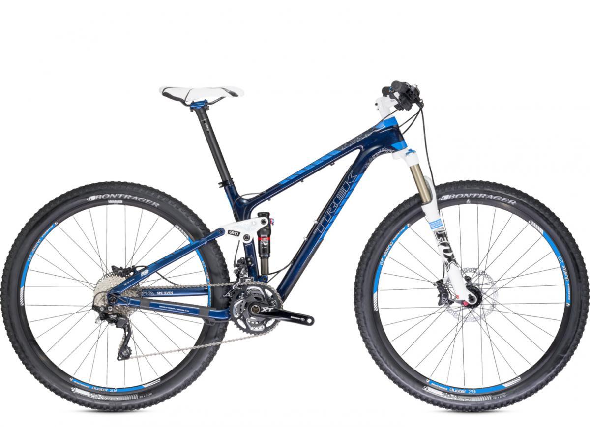 Trek Fuel EX 9.7 29: A blue and white Trek mountain bike with a lightweight frame, featuring front suspension and knobby tires for off-road traction. The bike includes Shimano components and Bontrager tires, showcasing a modern design suitable for trail riding. The bike is displayed against a white background.