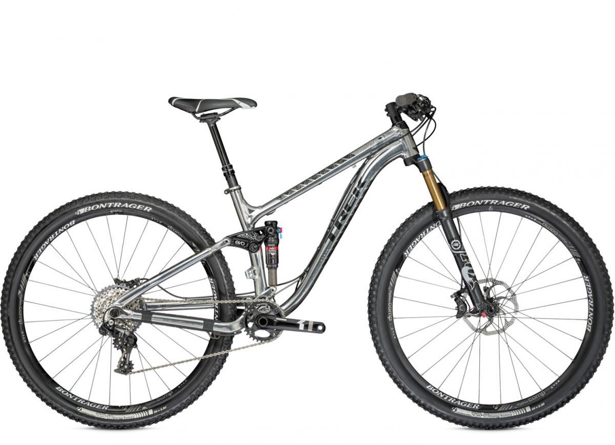Trek Fuel EX 9 29 XO1: A silver mountain bike with a lightweight frame, featuring front suspension, wide tires, and a sleek design. The bike is equipped with a shock absorber, a derailleur system, and has Bontrager tires, showcasing its readiness for off-road trails.