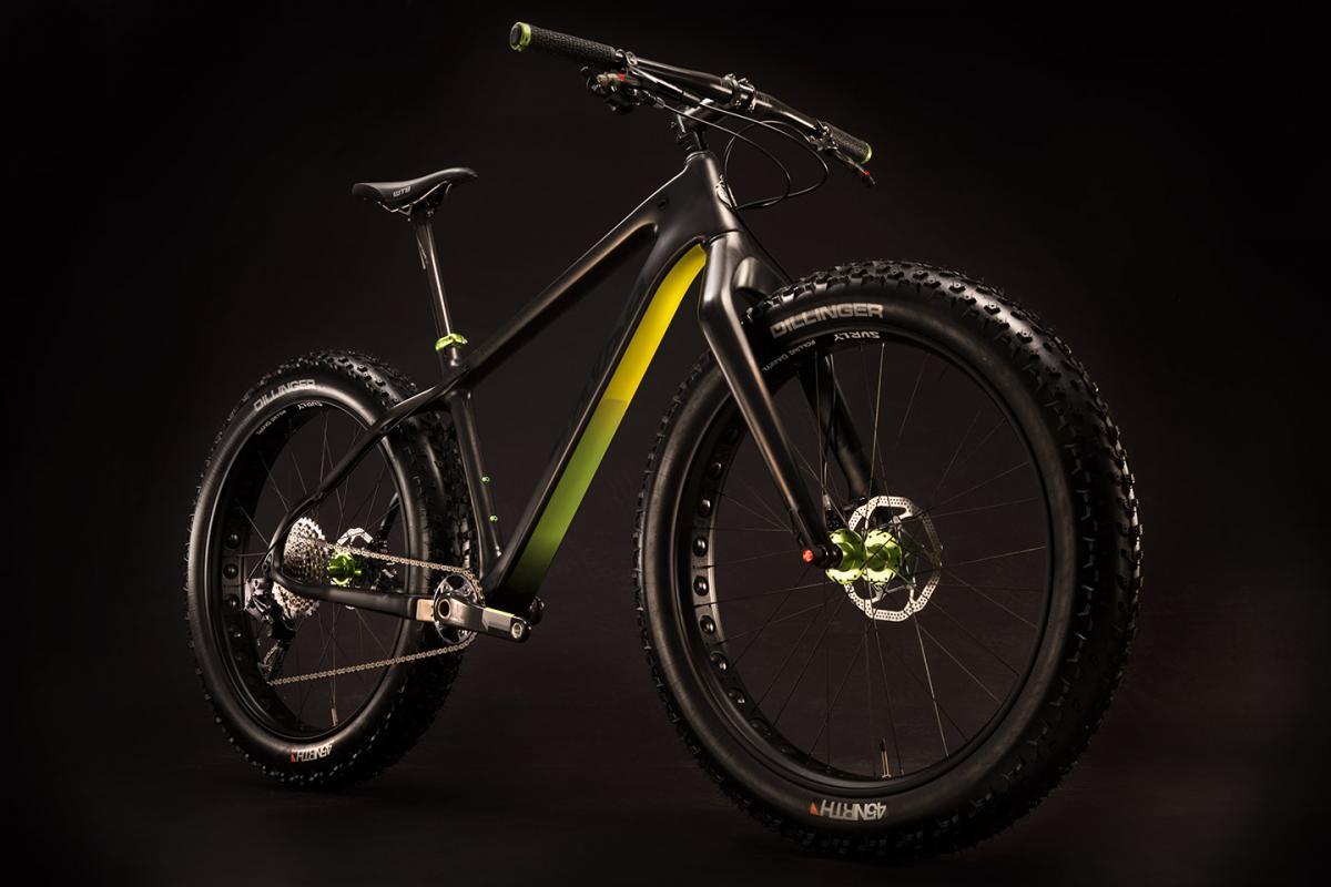 Salsa Beargrease Carbon XX1: A sleek black fat bike with green accents is positioned on a dark background. The bike features wide, knobby tires designed for off-road terrain, a sturdy frame, and high-quality components, showcasing its durability and modern design.