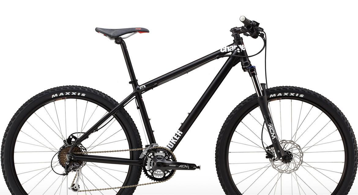 Charge Cooker 1: A black mountain bike with a lightweight frame, featuring disc brakes and rugged Maxxis tires. The bike has a sleek design, adjustable seat, and a front suspension fork suitable for off-road trails.