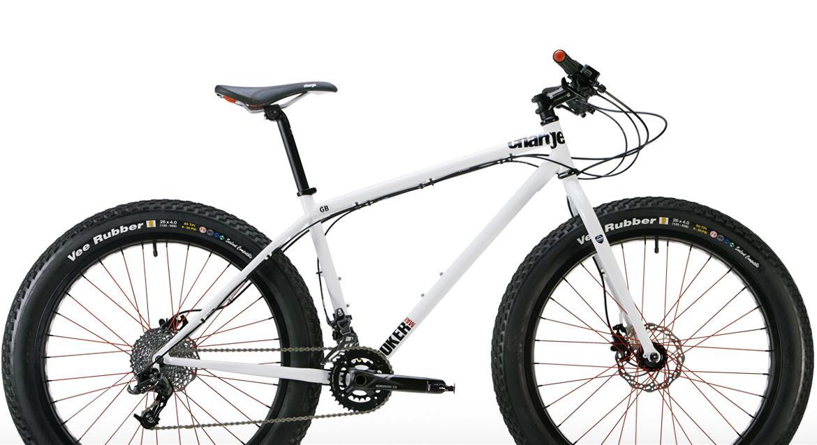 Charge Cooker Maxi: A white fat tire bike with red accents, featuring a sturdy frame and wide tires. The bike has a single gear setup, a black seat, and handlebars equipped with brake and gear shifting controls.